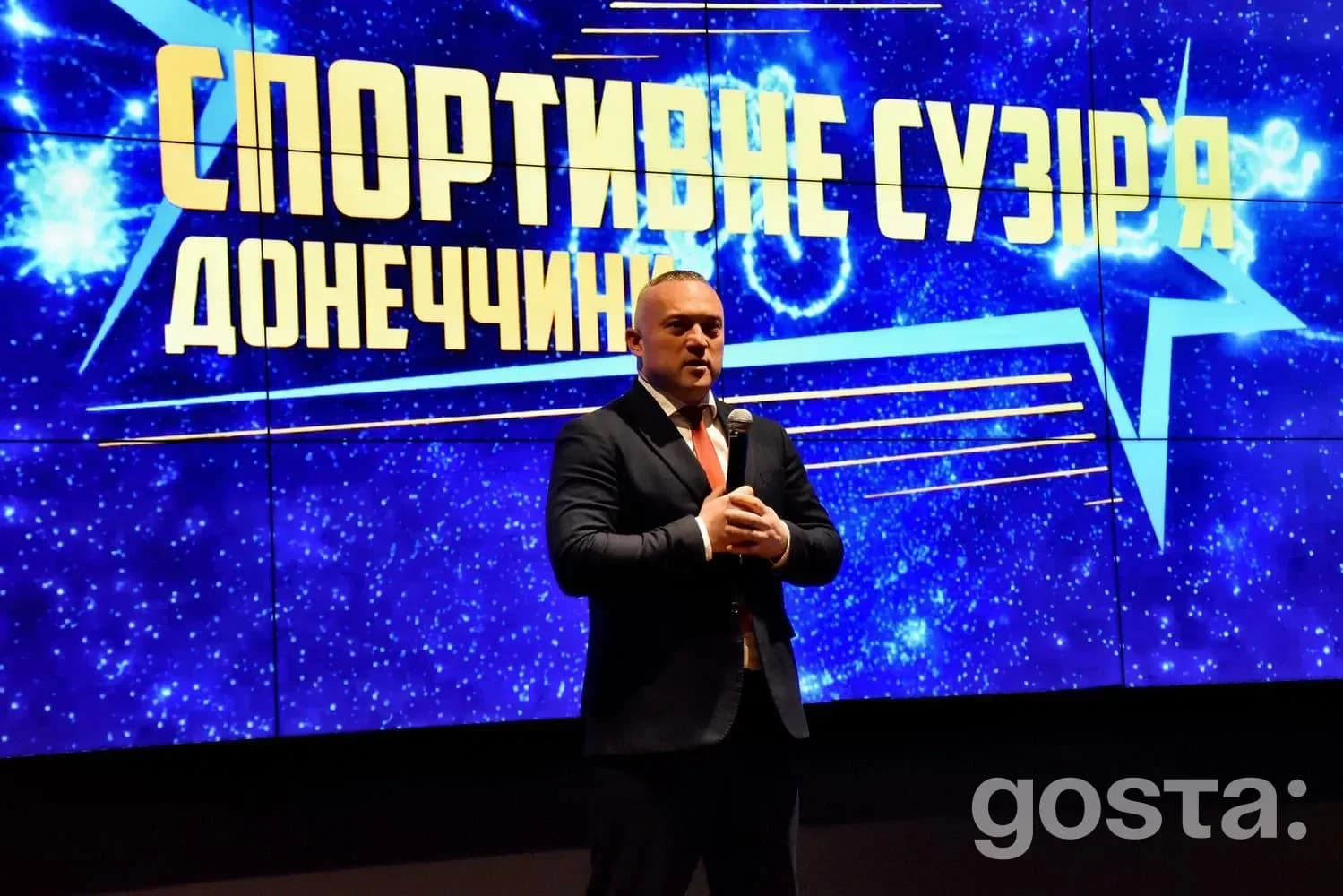 На сцені церемонії «Спортивне сузір’я Донеччини – 2025» виступає спікер, тло з назвою події.