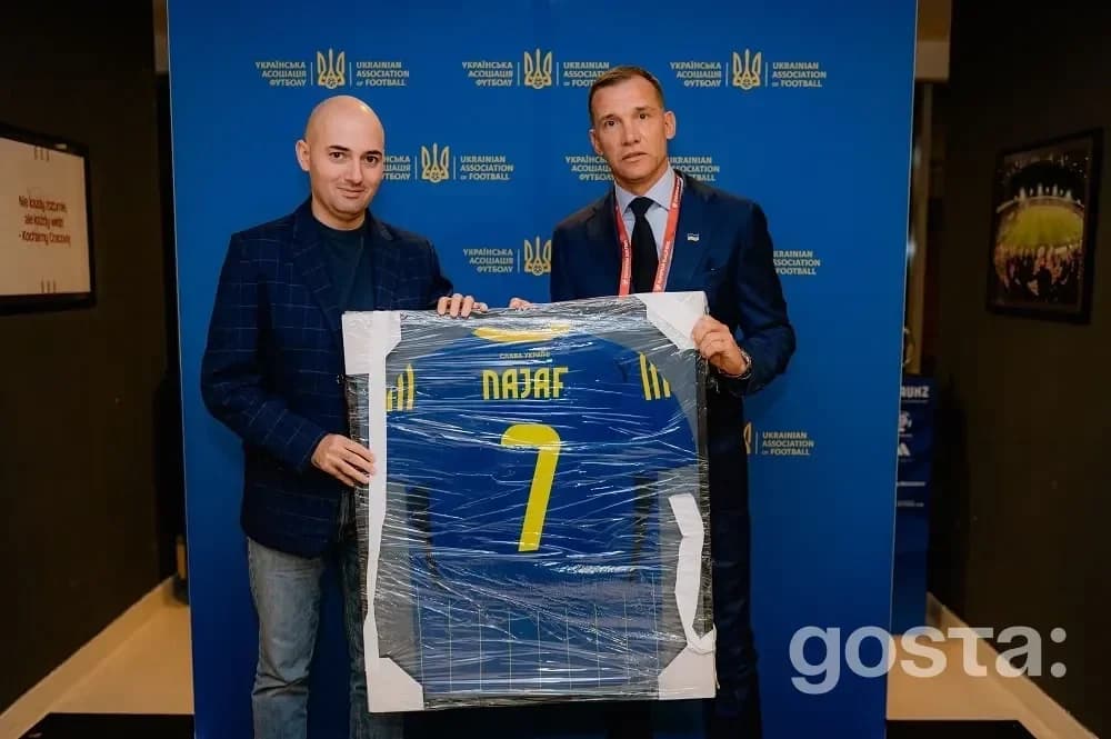 Офіційна зустріч УАФ і АФФА: двоє представників тримають подарункову футболку України перед відбором ЧС‑2026 у Кракові.