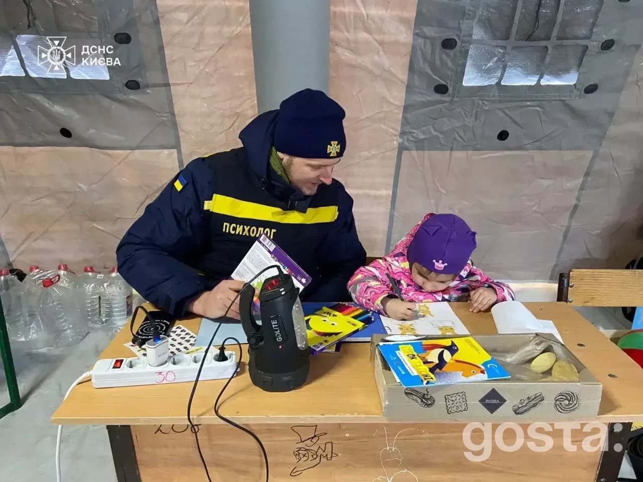 Психолог ДСНС допомагає дитині малювати у Пункті незламності Києва, січень 2026.