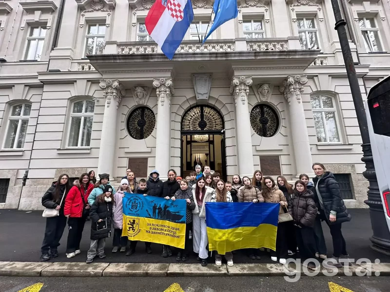 Діти загиблих захисників тримають українські прапори перед будівлею в Хорватії, підтримка МВС, лютий 2026.