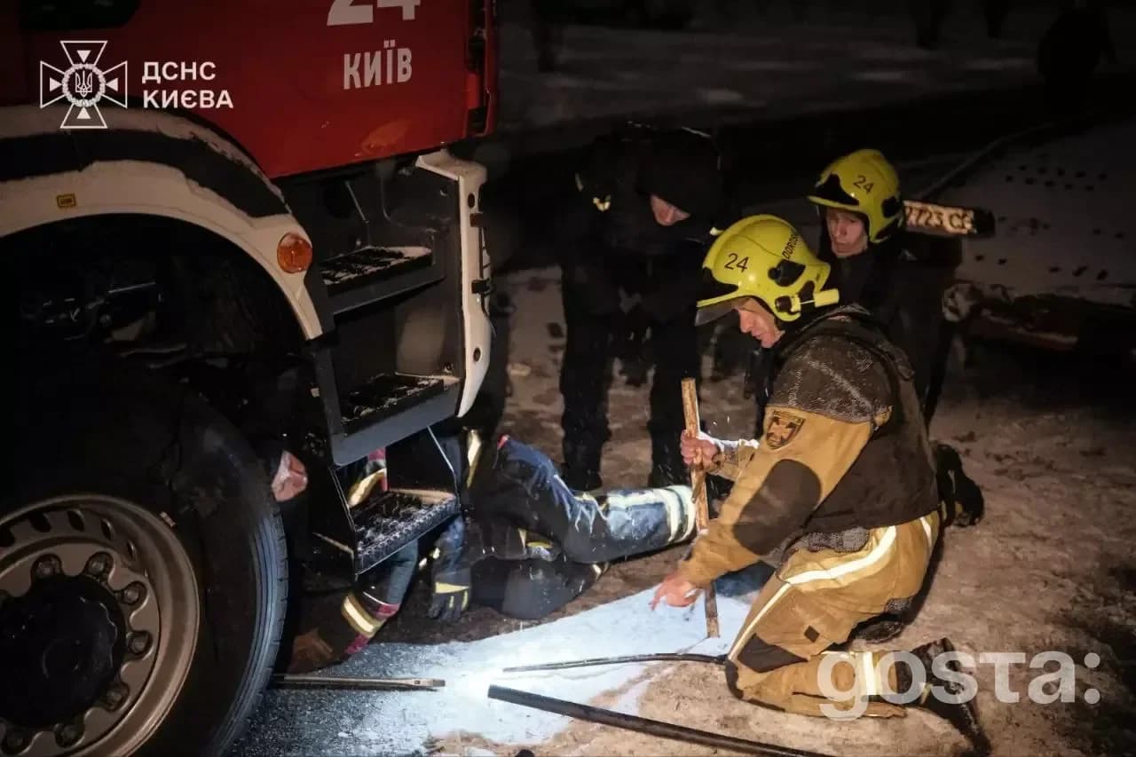 Alt text: "Рятувальники ДСНС України на місці події вночі, допомагаючи постраждалому під час обстрілу в Києві.