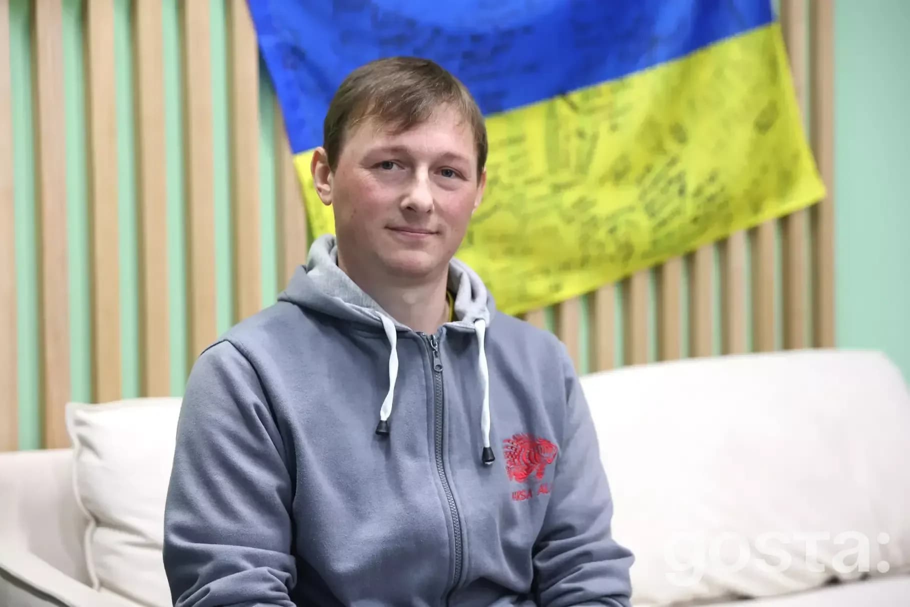 Солдат батальйону "Спартан" Нацгвардії України частується під час реабілітації, на фоні синьо-жовтого прапора.