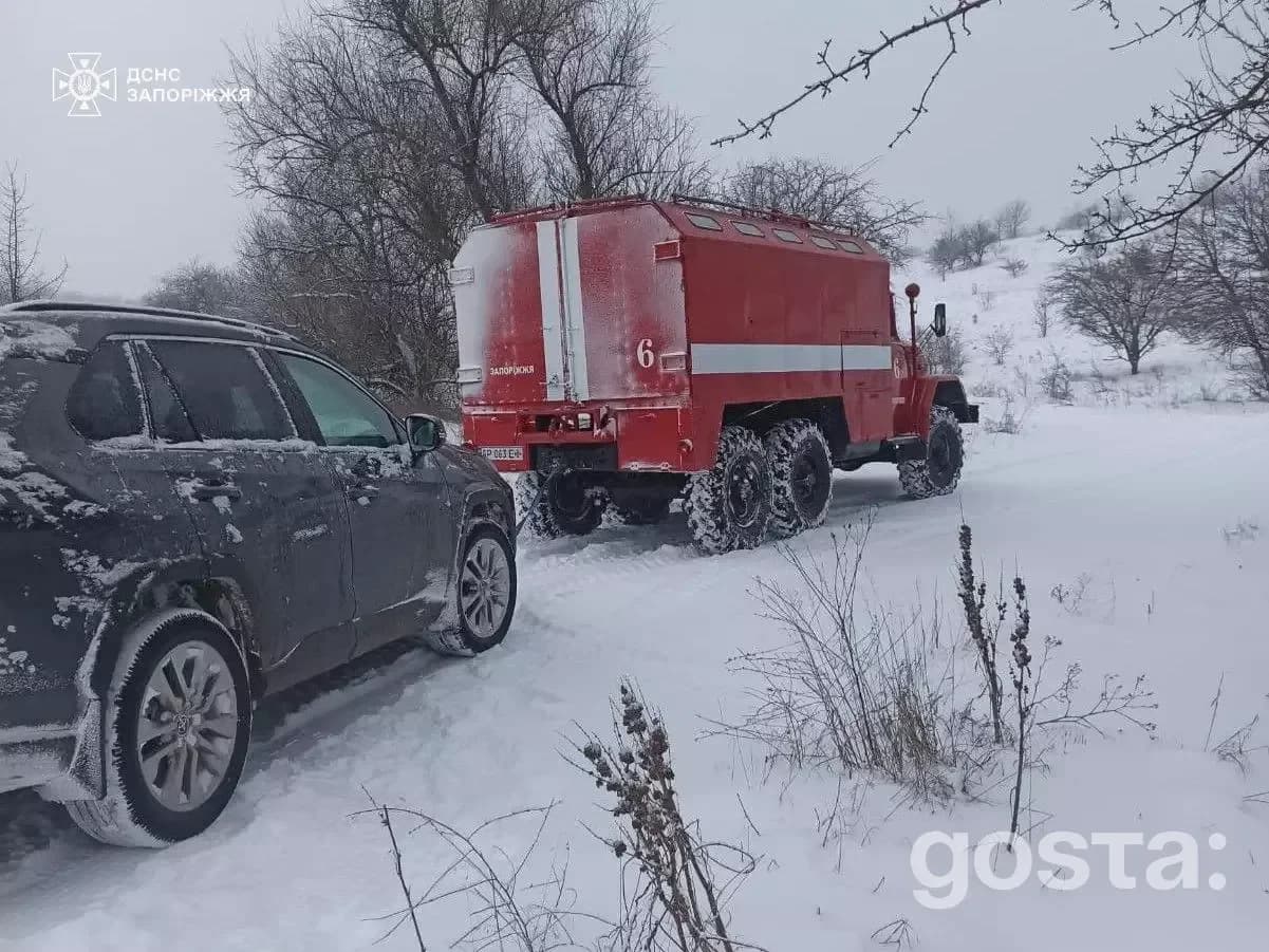 Рятувальники ДСНС України на сніговій дорозі з пожежним автомобілем під час зимових умов у сільській місцевості.