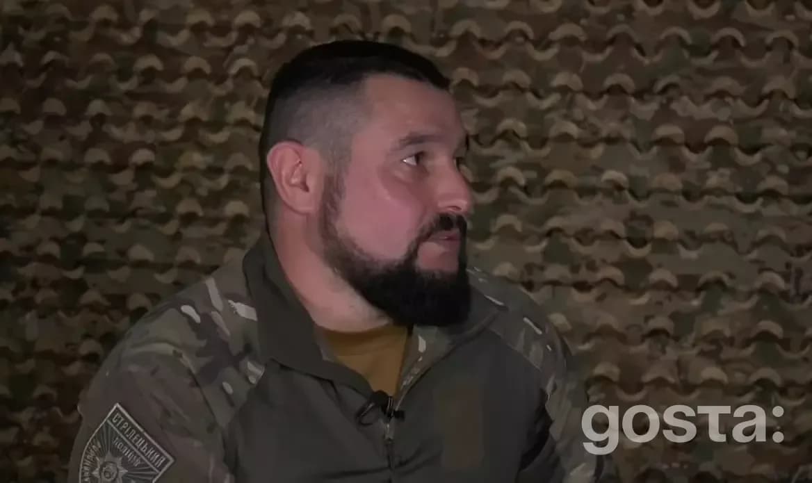 Боєць у військовій формі на тлі камуфляжної сітки, інтерв'ю для "Подробиці".