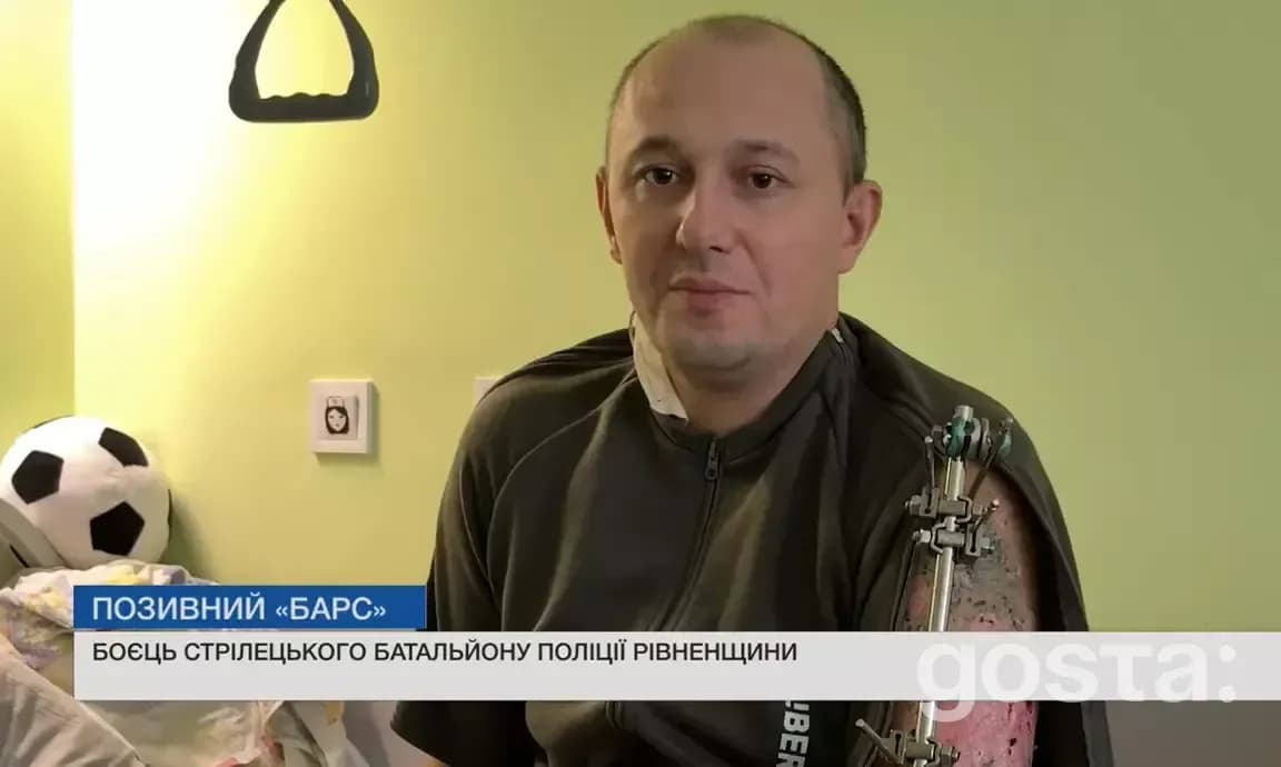 Боєць поліції з позивним "Барс" в лікарні після поранення; праве плече на швейцарській подушці, футболка, фон кімнати.