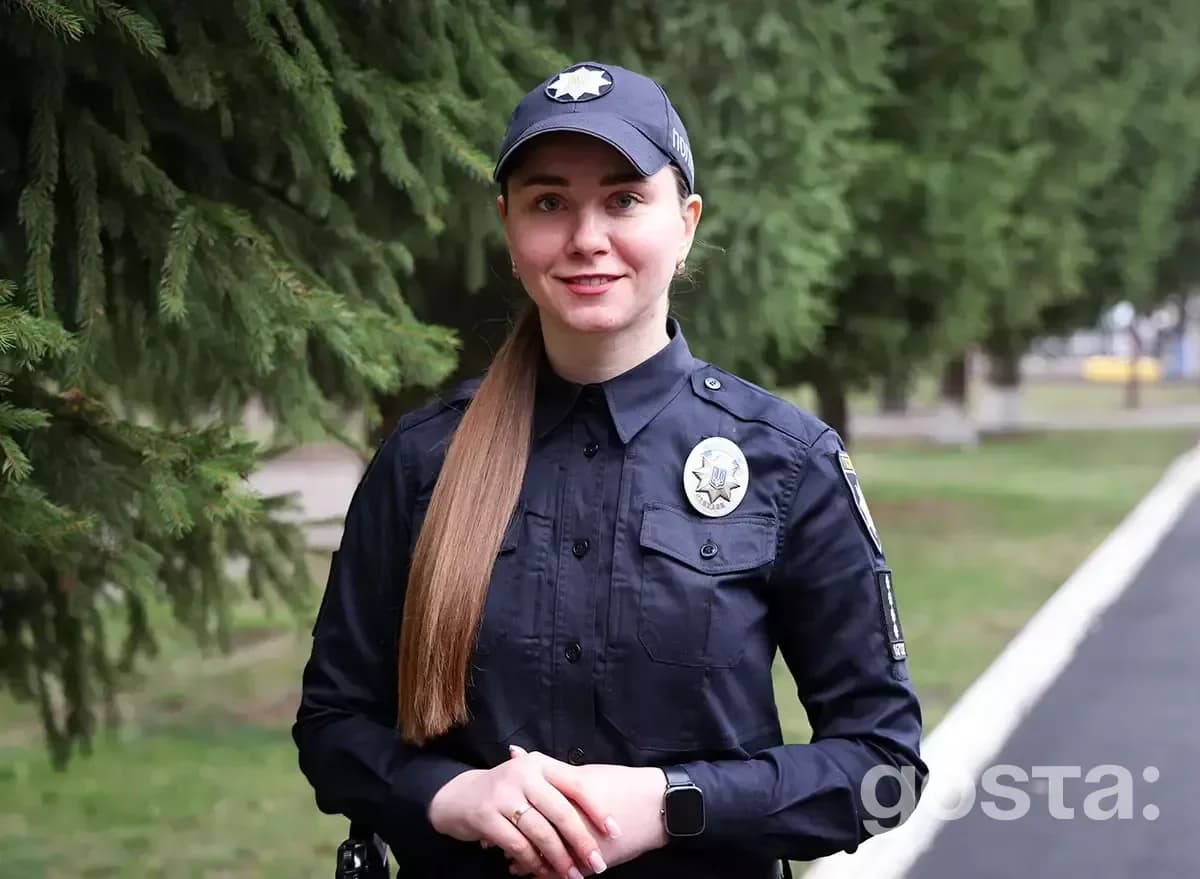 На фото офіцерка поліції в формі стоїть на тлі зеленої алеї, представляючи освітню безпеку в Україні.