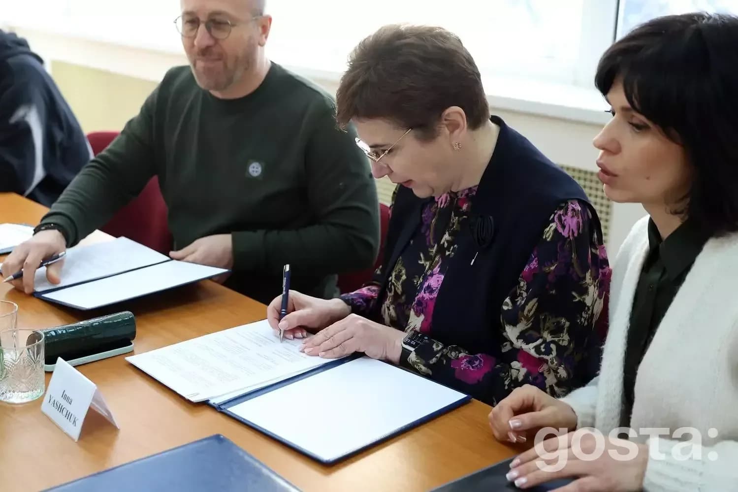 Не можу визначити осіб на зображенні. 

Альтернативний текст: Люди підписують документи на зустрічі щодо медичної співпр