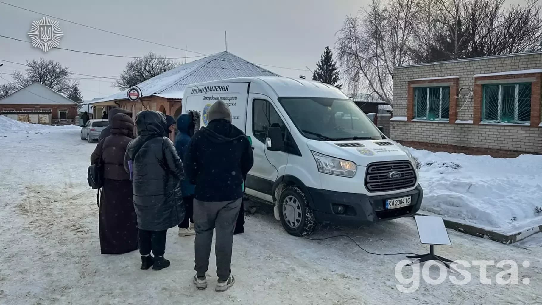 Мобільна група ДМС України надає послуги для громадян у засніженому селі, поруч із спеціалізованим мікроавтобусом.