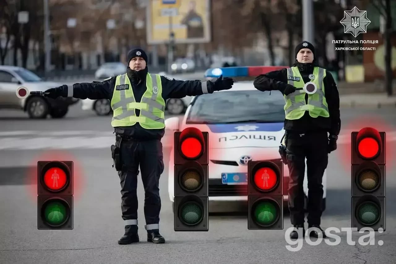 На зображенні двоє поліцейських регулюють дорожній рух, стоячи перед патрульною машиною.