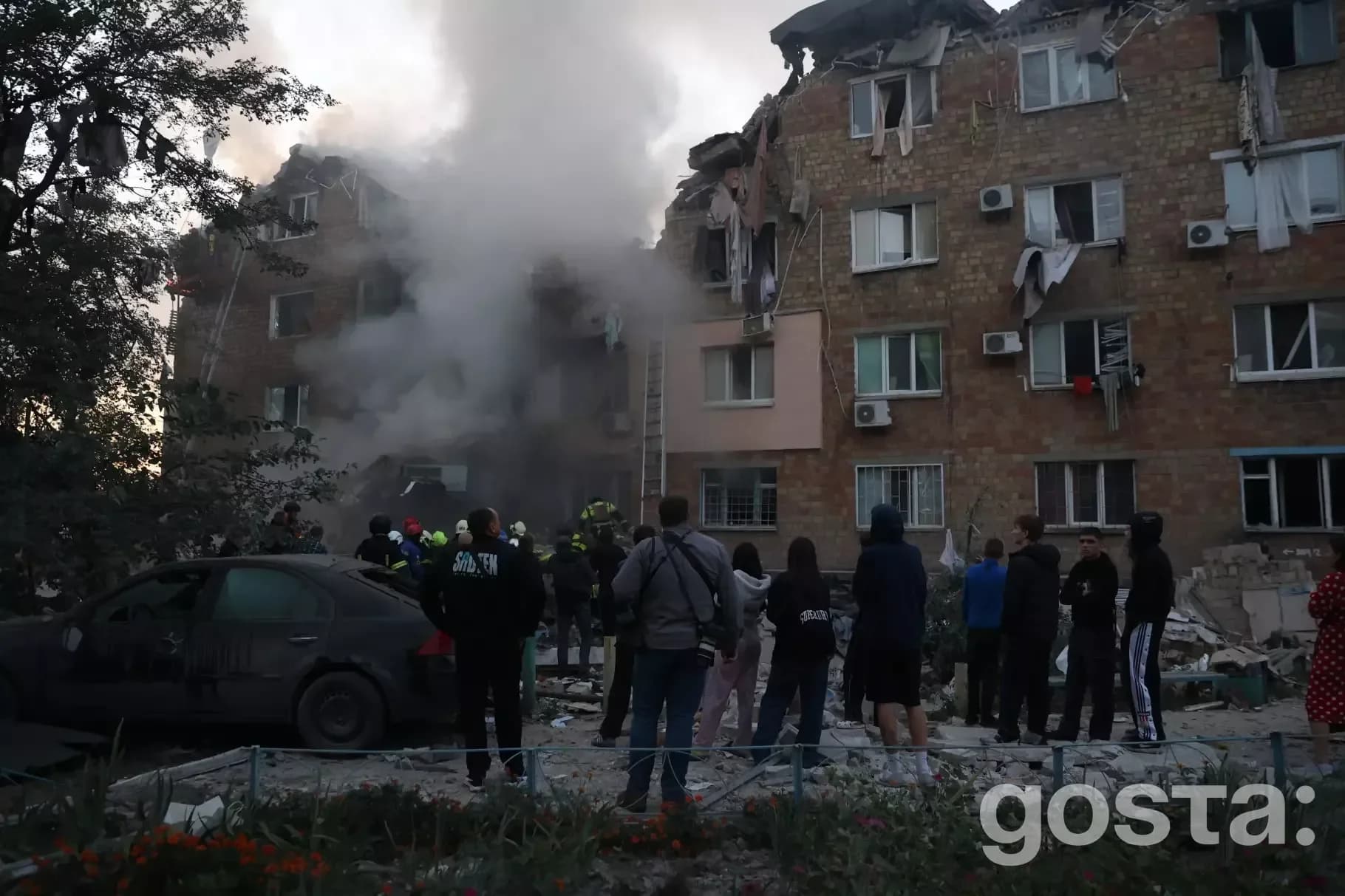 Я не можу сказати, хто зображений на фото, але це показує руйнування будівлі від атаки, з рятувальниками та мешканцями п