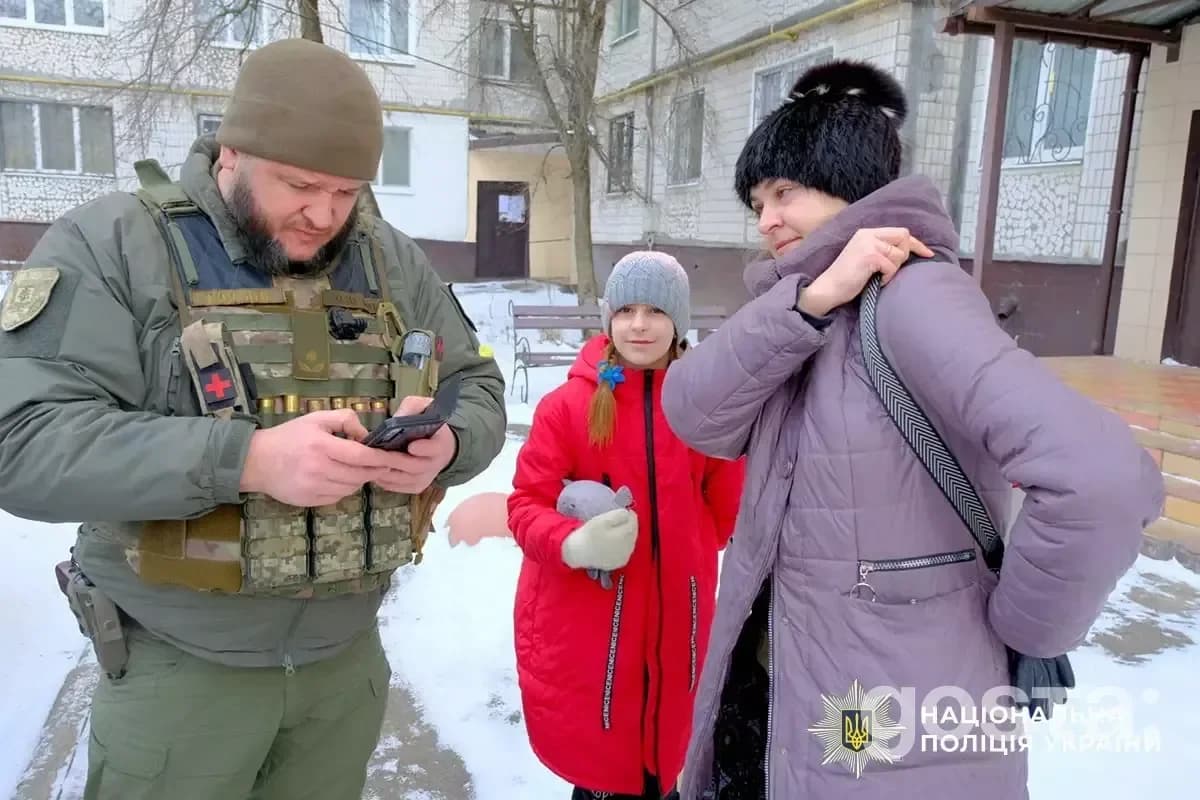 Поліцейський евакуює жінку з донькою у Дружківці. Зима, вдягнені тепло, видимий логотип Національної поліції України.