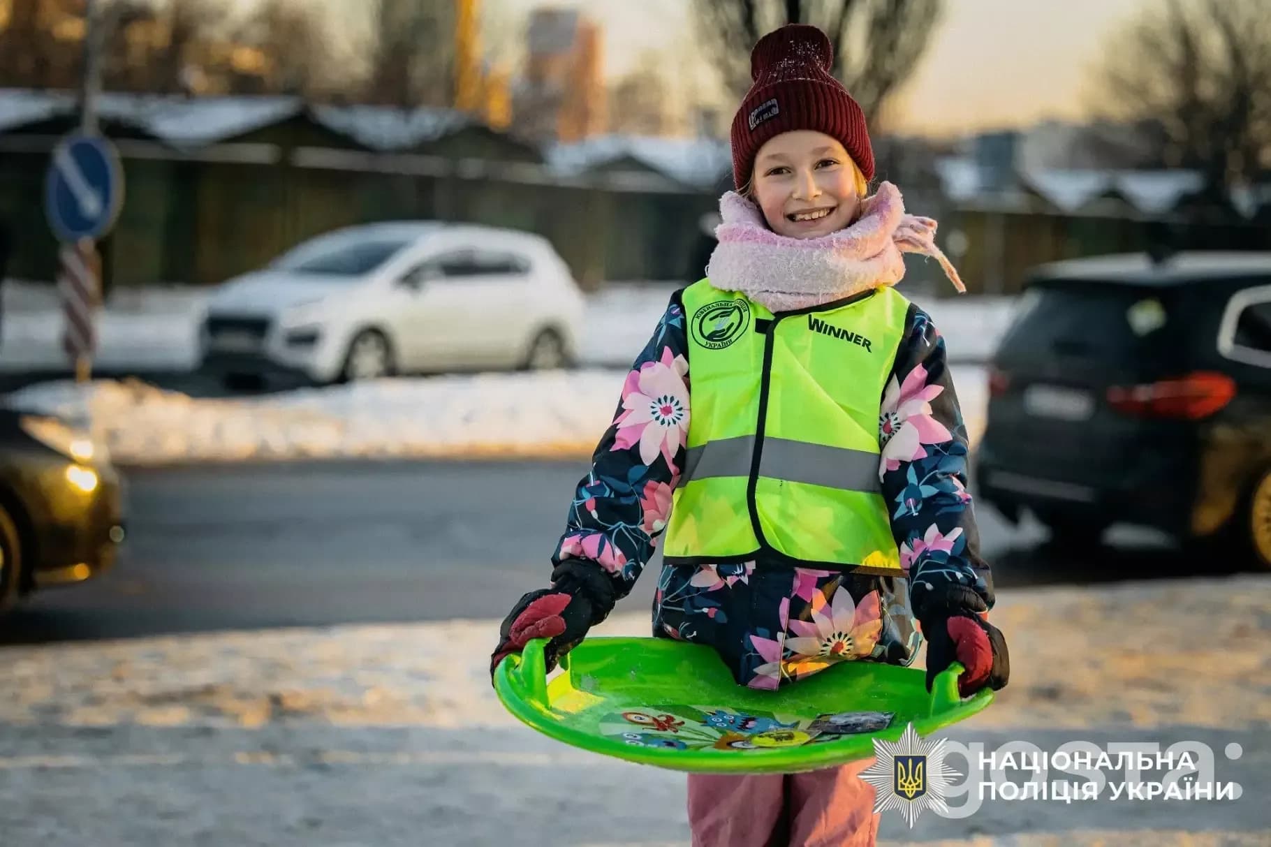 Дитина в світловідбивальному жилеті гуляє зимою, захід Національної поліції України для безпеки на дорозі.