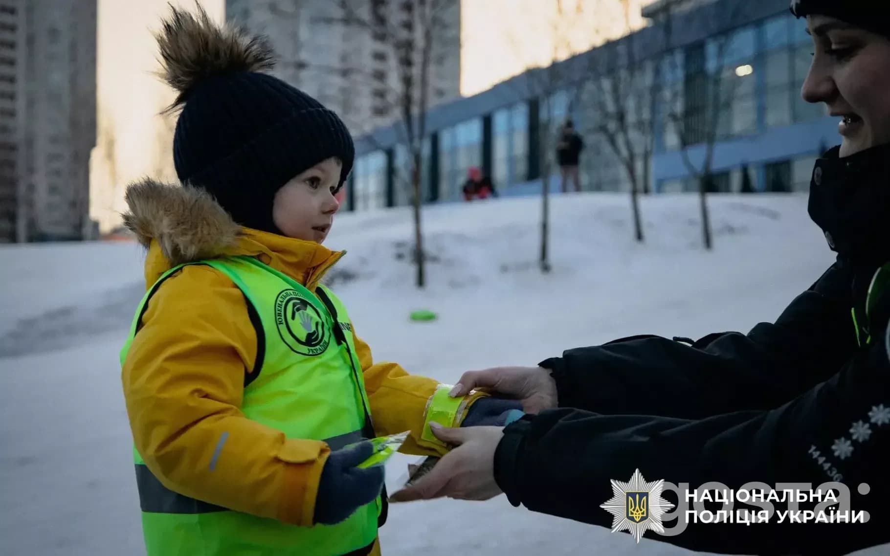 Ювенальні поліцейські навчають дітей безпеці, роздаючи світловідбивальні елементи в зимовий період.