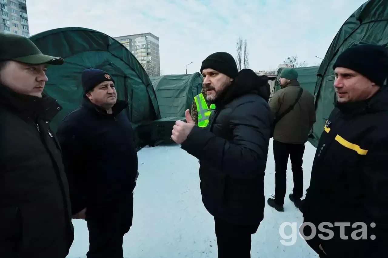 Люди обговорюють розгортання великого намету обігріву в сніговому дворі житлового комплексу в Києві.