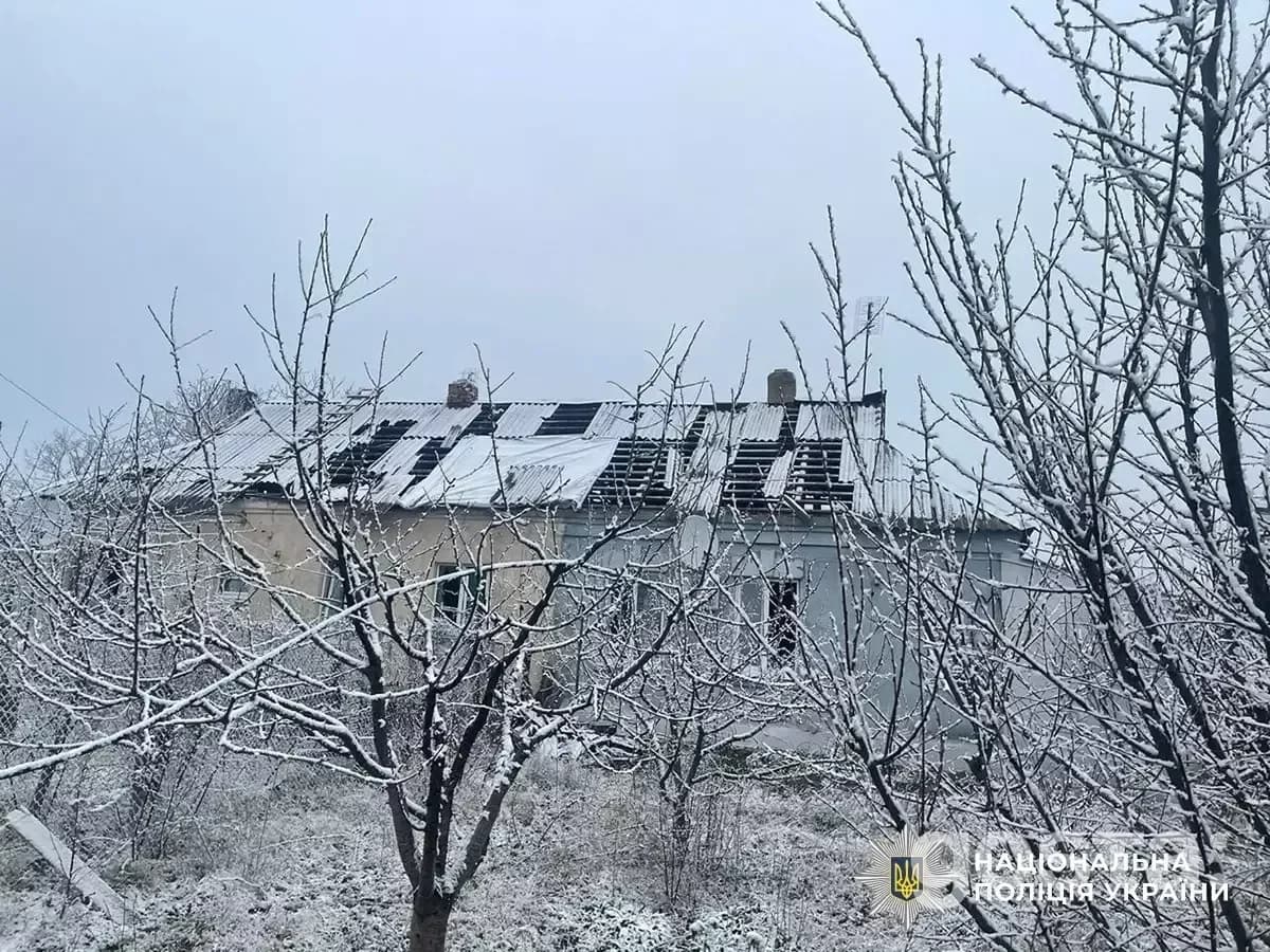 Пошкоджений будинок у засніженому лісі, наслідки обстрілів в Україні. Видно зруйнований дах і пошкоджену територію.