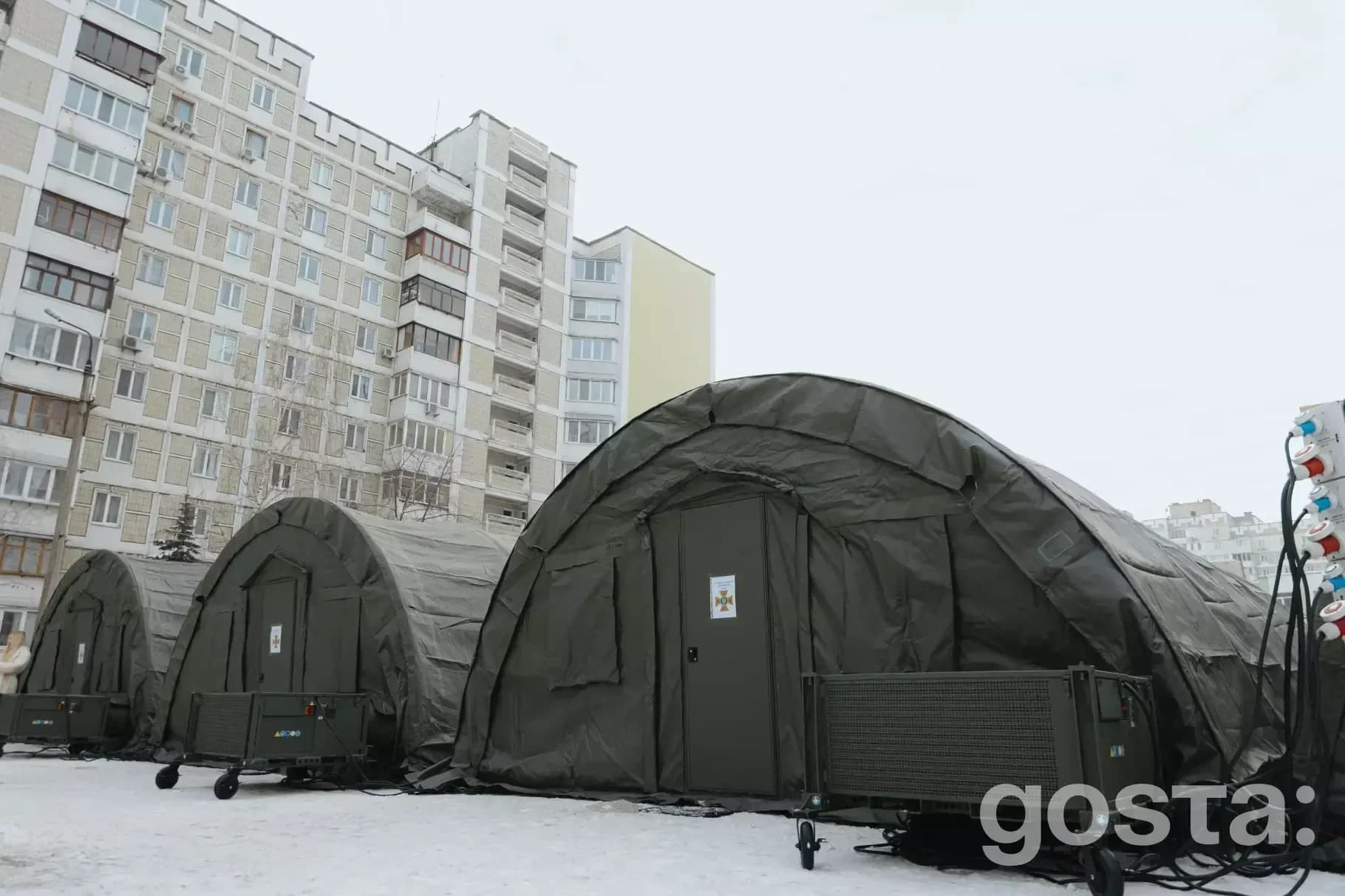 Три тимчасові намети ДСНС для пунктів обігріву в зимовому Києві на тлі багатоповерхівок.