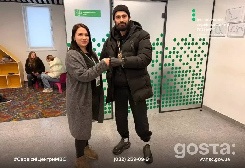 У сервісному центрі МВС двоє людей стоять перед стіною з логотипом, інші люди сидять на фоні.