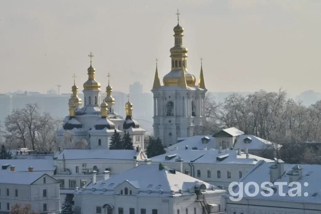 Засніжені куполи монастирських корпусів Києво-Печерської лаври на тлі зимового пейзажу.