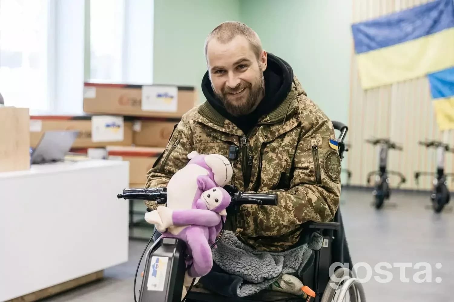 Захисник України на інвалідному візку з електроприводом, тримає іграшку в клініці, демонструючи реабілітацію.