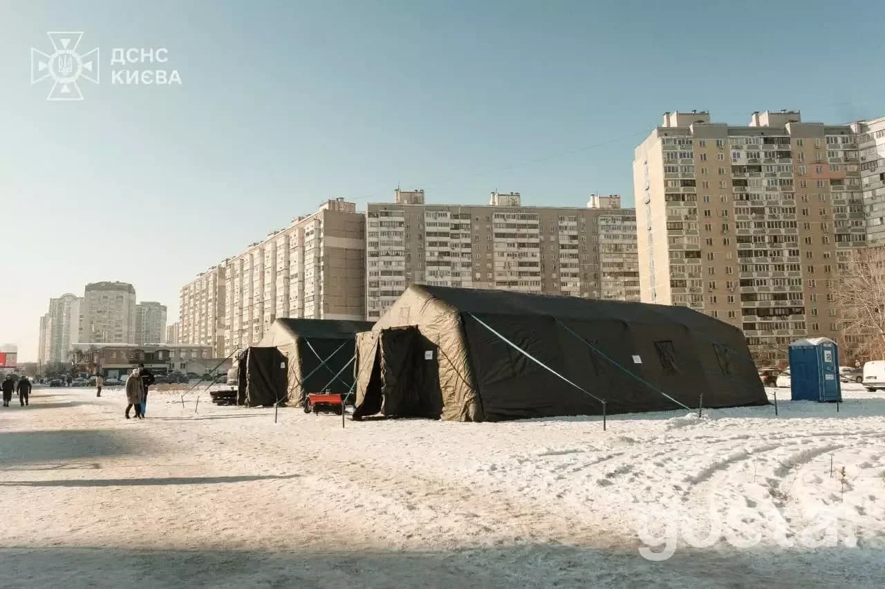 Наметове містечко пунктів обігріву на снігу в Києві, з логотипом ДСНС на передньому плані.