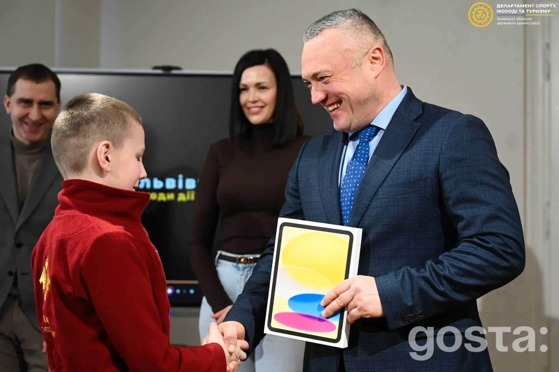 Заступник міністра нагороджує дитину планшетом на заході, присвяченому розвитку масового спорту у Львові.