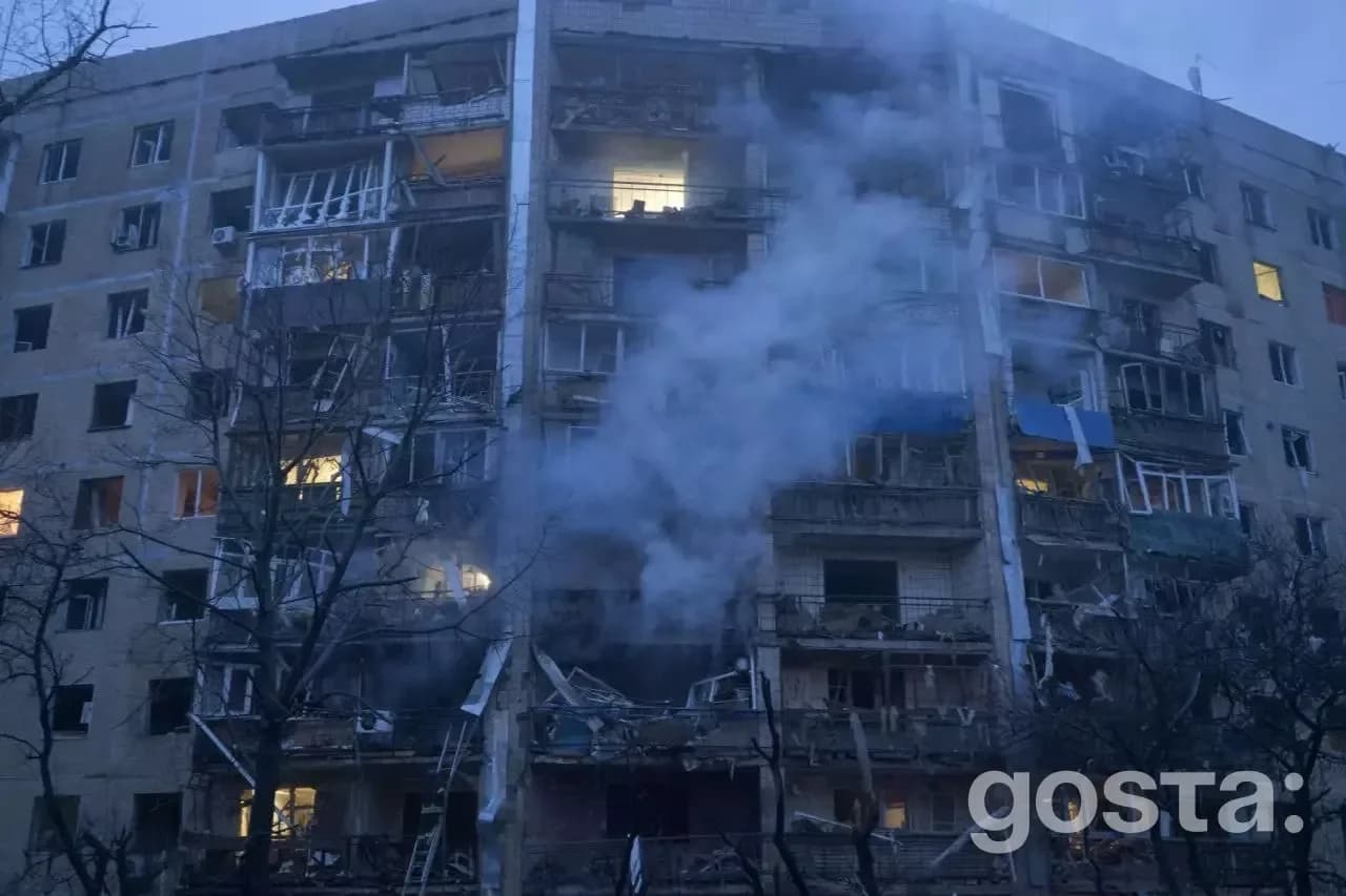 Житловий будинок в Україні зазнав руйнувань від обстрілів, дим підіймається з вікон, видно значні пошкодження фасаду.