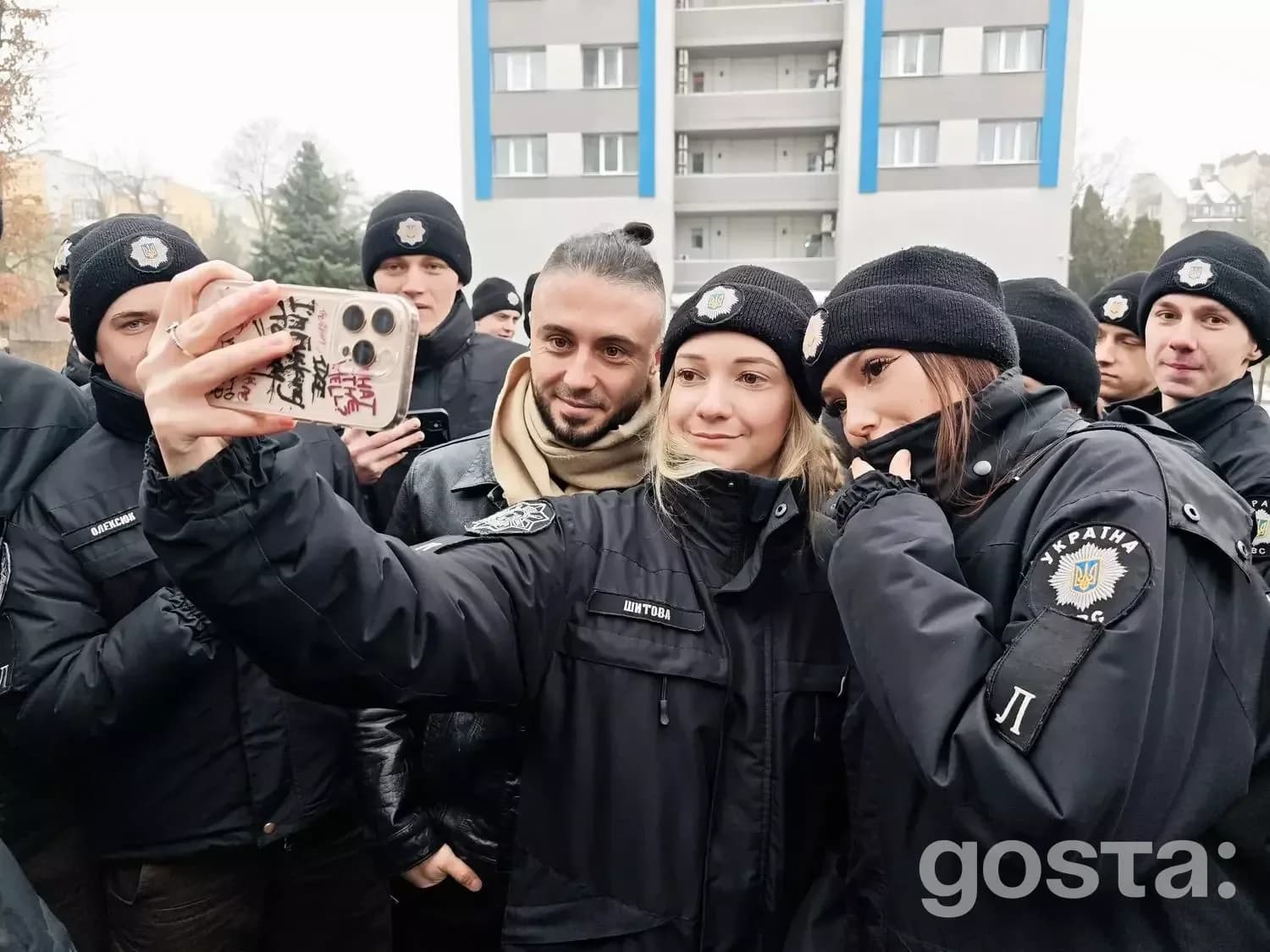 Я вибачаюсь, але я не можу розпізнати, хто на зображенні. 

Опис зображення: Ліцеїсти МВС фотографуються з учасниками гу