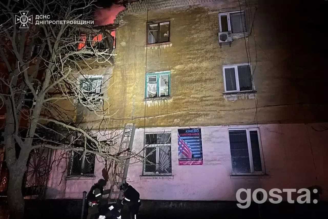Пожежа в житловому будинку після обстрілу в Україні, рятувальники працюють на місці події в нічний час.