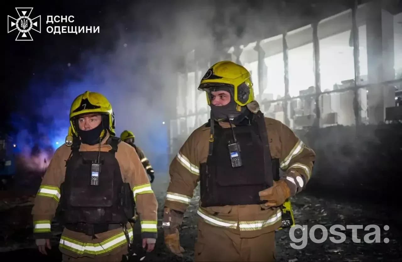 Пожежники в спецодязі працюють на місці обстрілу в Україні, ніч, дим, зруйнована інфраструктура.
