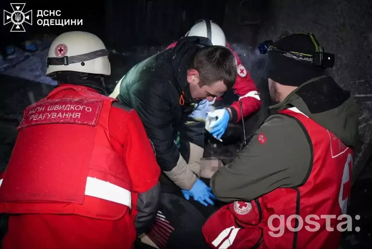 Рятувальники надають допомогу постраждалому після обстрілу в Україні, працюють вночі у зимовому одязі.