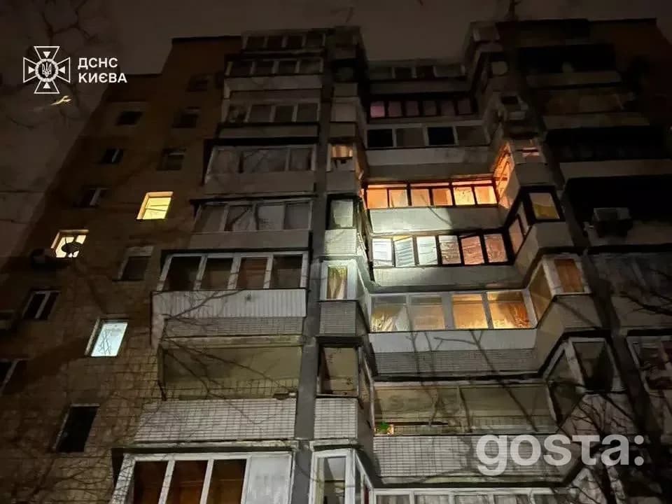 Освітлена багатоповерхівка вночі після обстрілу; частина будівлі без світла, Київ.