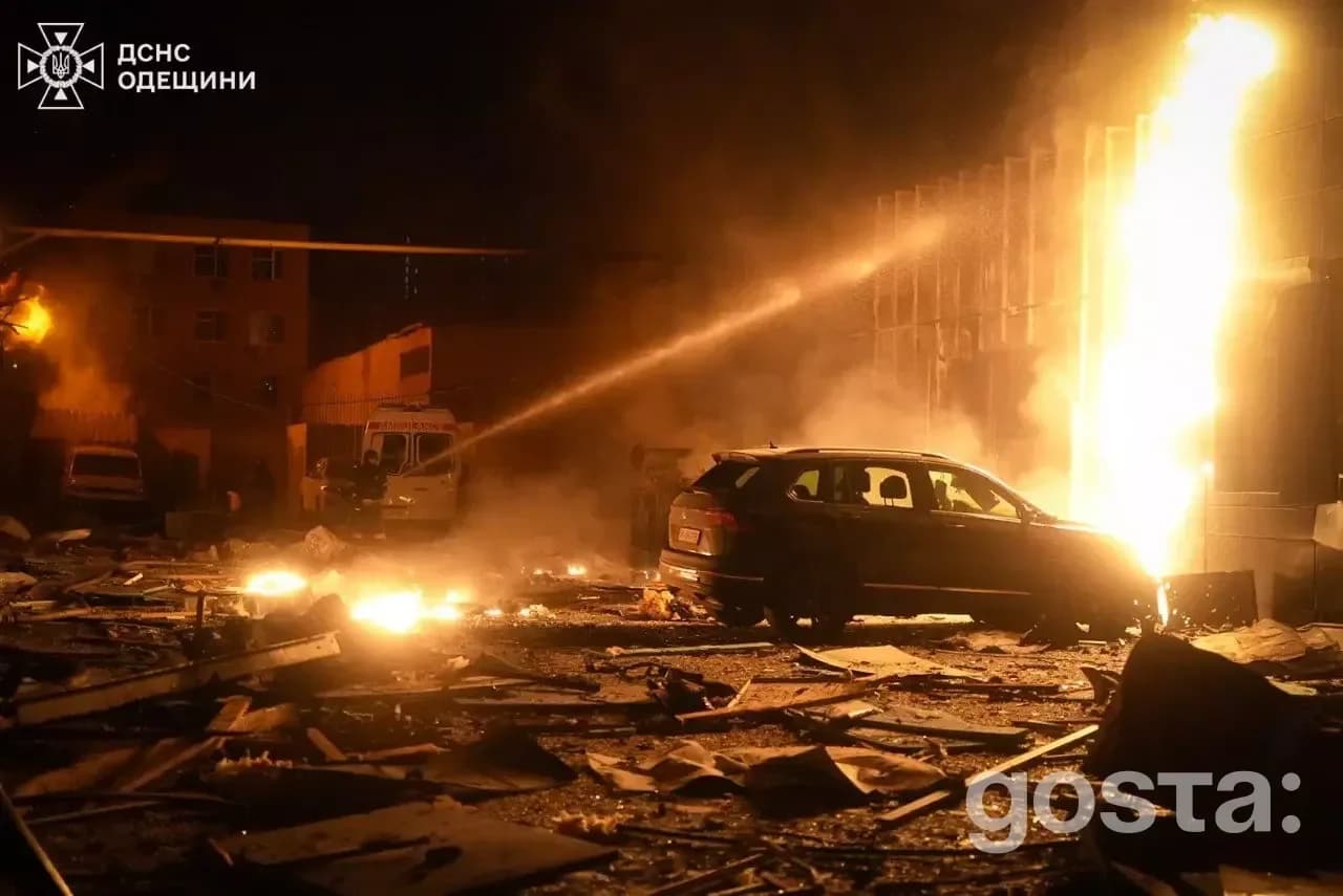Пожежа після обстрілу в Одесі: згорілі автомобілі, пошкоджена будівля, рятувальники гасять вогонь.