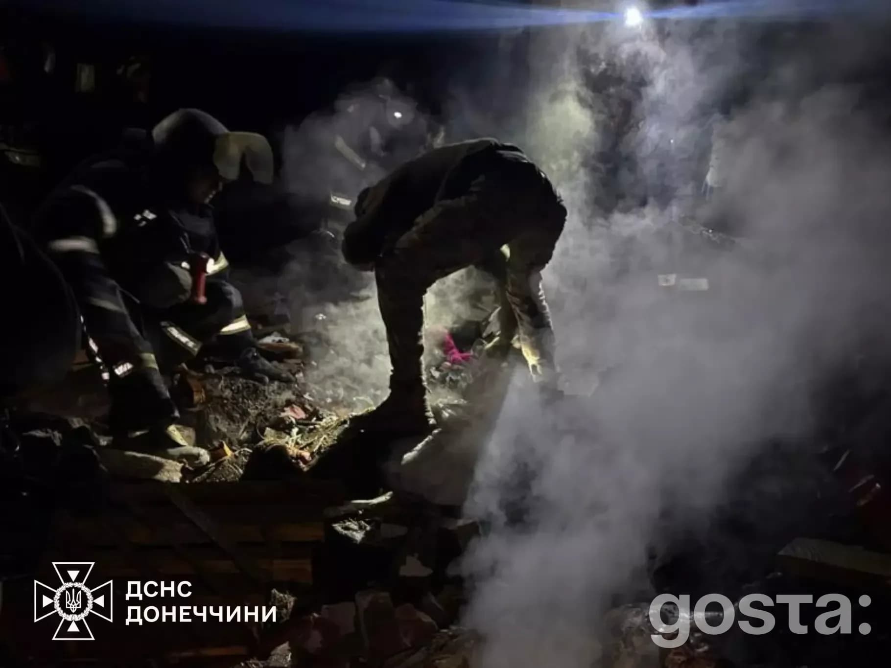 Рятувальники працюють на місці обстрілу в Донецькій області, нічна сцена, густий дим, пошкоджені будівлі.
