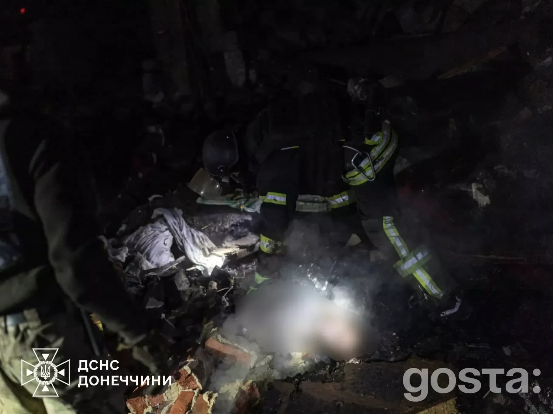 Рятувальники працюють на місці обстрілу в темряві; пошкодження інфраструктури, присутність диму та уламків.