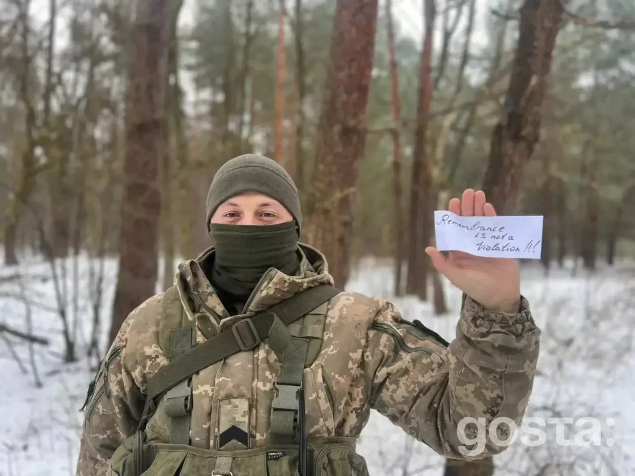 Військовослужбовець у камуфляжі в лісі тримає табличку з написом «Пам’ять – це не порушення!».