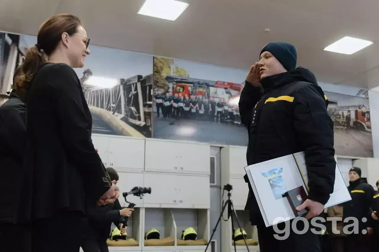 Юлія Свириденко вручає нагороду рятувальнику ДСНС України. На фоні фото рятувальників, поліцейських.