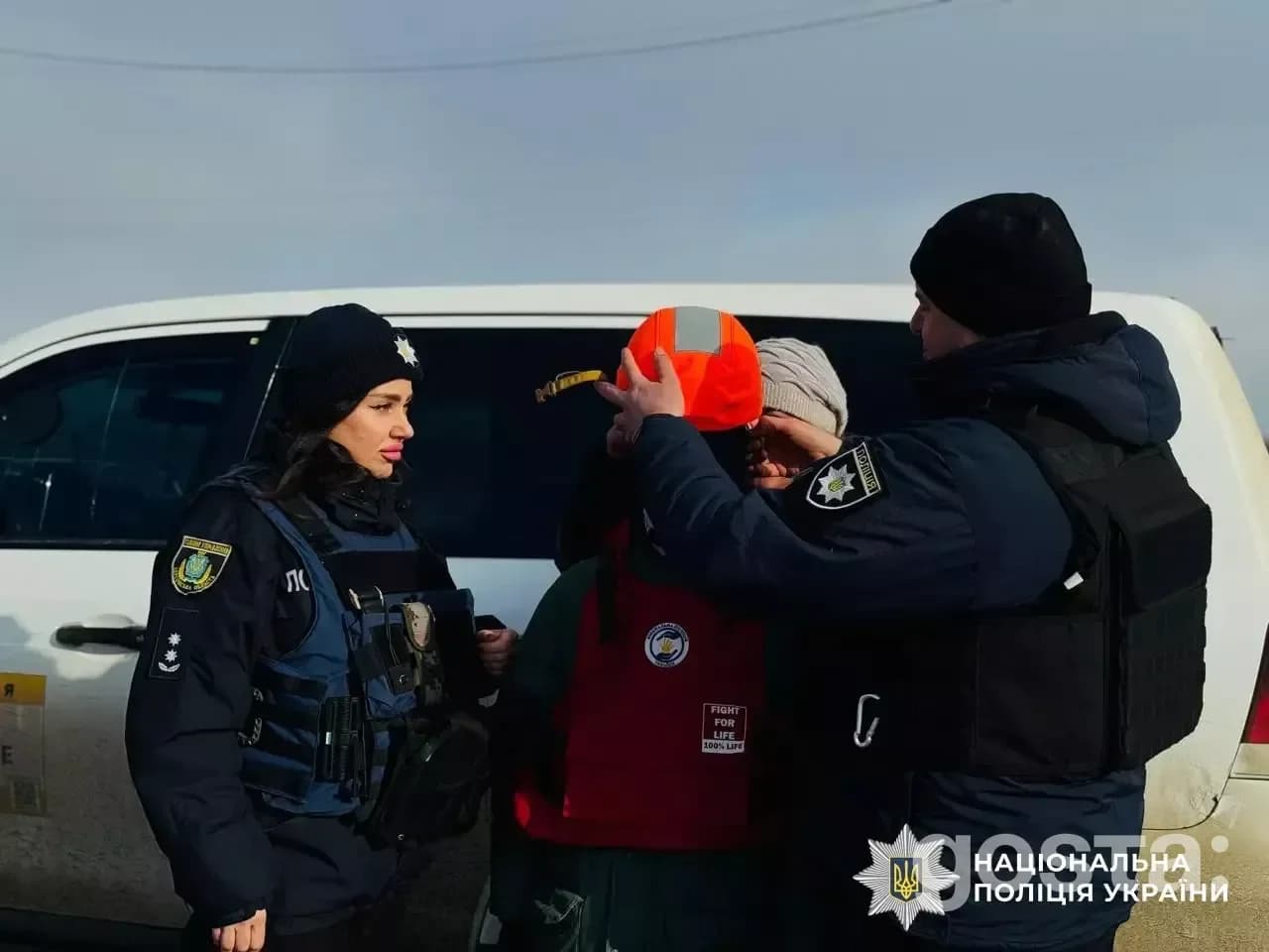 На фото: евакуація родин поліцією та волонтерами на Херсонщині, співробітники допомагають з безпекою біля авто.