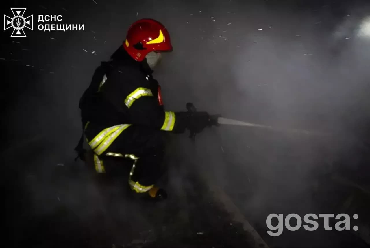 Рятувальник гасить пожежу після обстрілу, густий дим заповнює повітря, видимі пошкодження інфраструктури.
