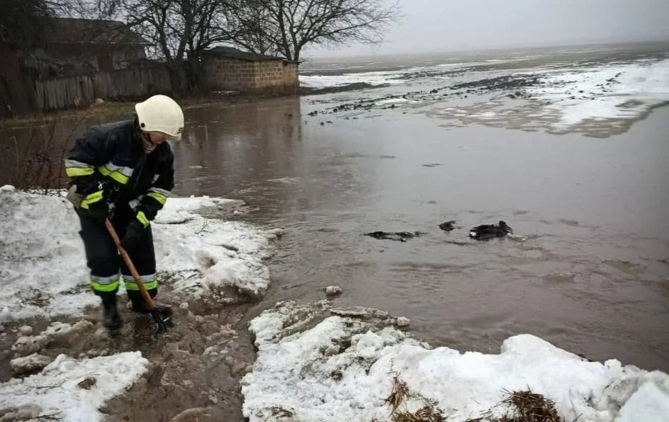 Працівник ДСНС з лопатою ліквідовує наслідки підтоплення річки