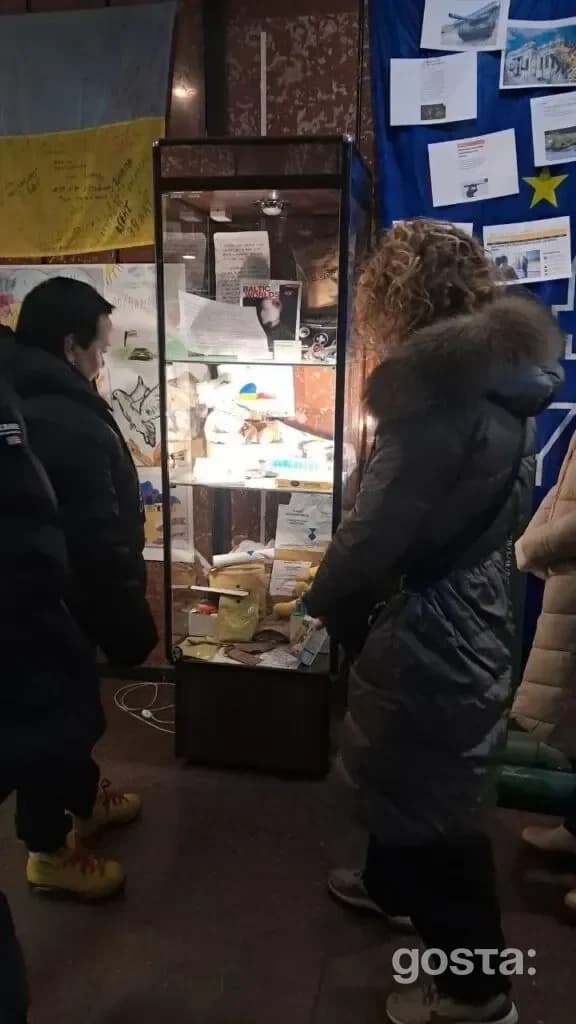 На фото відвідувачі оглядають експонати у скляній вітрині в SHELTER-ART SPACE в Дніпрі.
