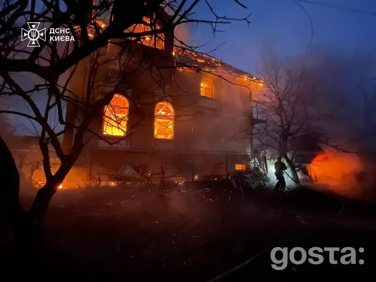 Emergency responders extinguish flames at a damaged building in Kyiv following a Russian attack, amid smoke and debris.