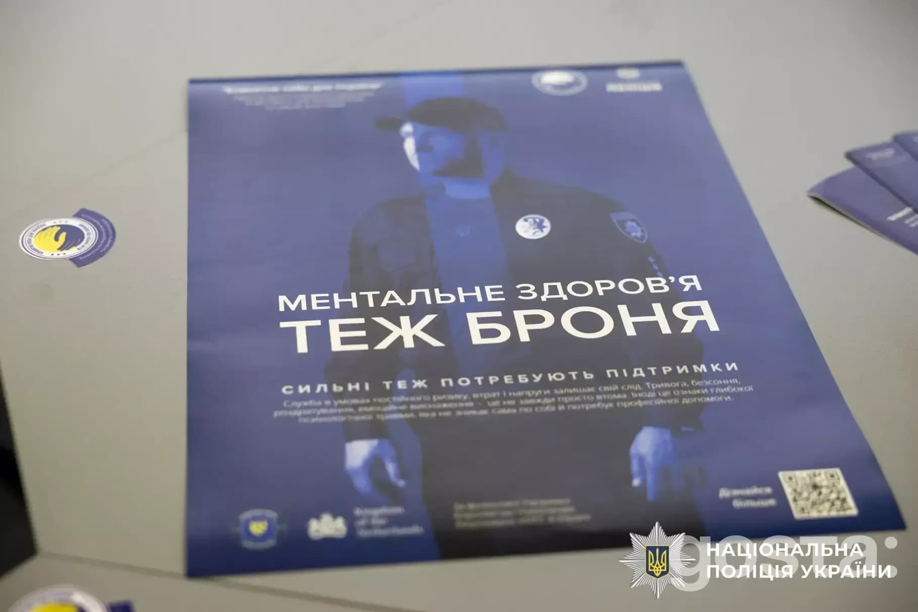 Не знаю, хто це. Постер «Ментальне здоров'я — теж броня» з символікою Національної поліції України.
