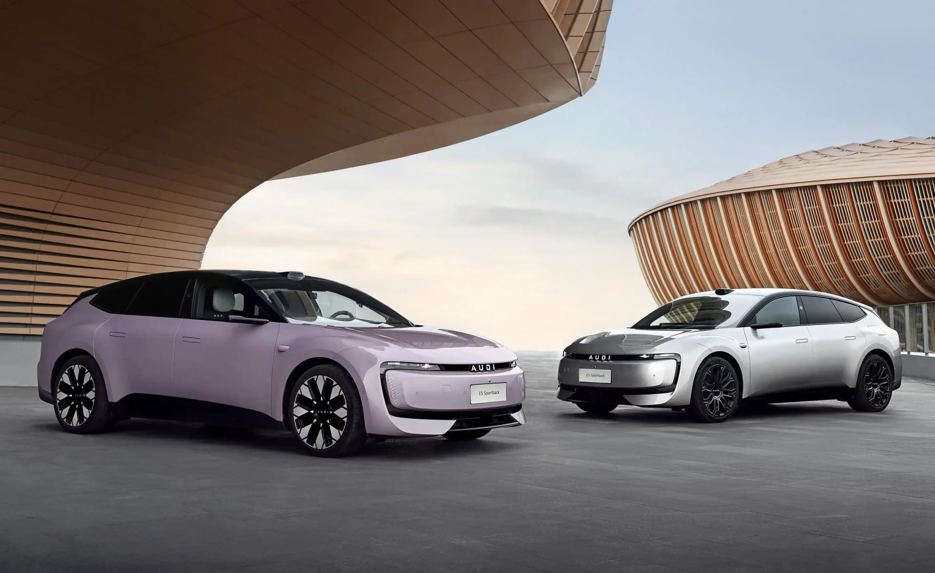 Two Audi e5 Sportback models showcasing bold colors before modern architecture